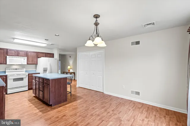 a living room with stainless steel appliances granite countertop a sink dishwasher a stove a refrigerator and a dining table with wooden floor