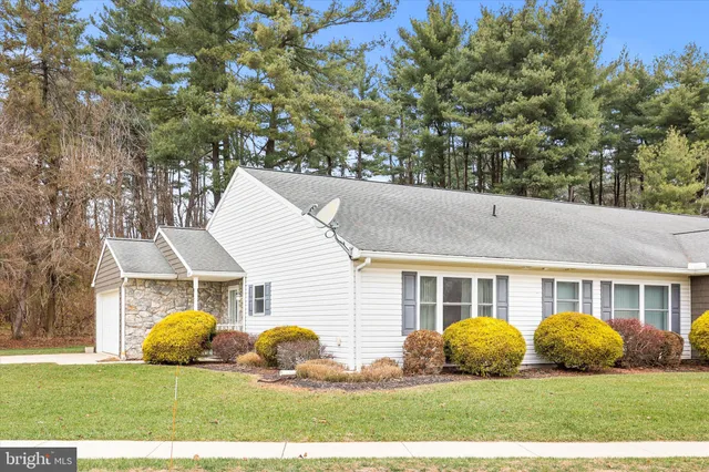 a view of a white house with a big yard and large trees