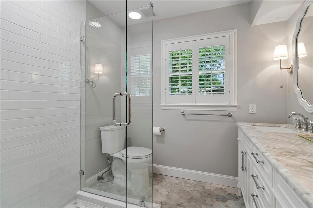 11439 Rosser Road Dallas, TX 75229 - Photo 19 of 35 a bathroom with a granite countertop toilet a sink a mirror and a window