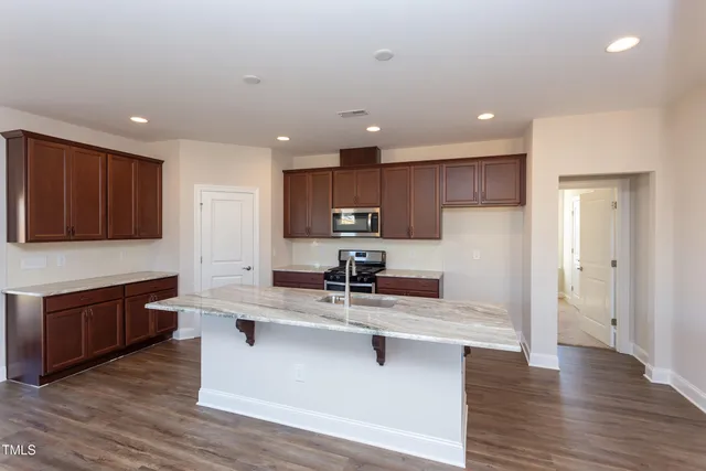 a kitchen with stainless steel appliances granite countertop a sink a stove a refrigerator and cabinets