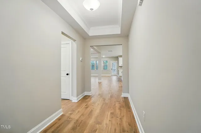 a view of a hallway with wooden floor and a bathroom