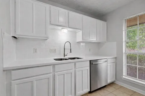 a kitchen with white cabinets and sink