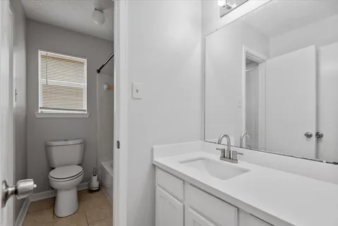 a bathroom with a granite countertop sink toilet and mirror