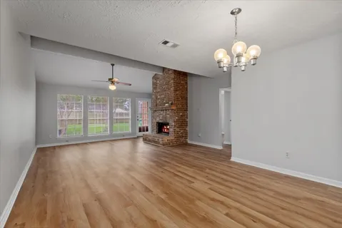 an empty room with wooden floor and large window