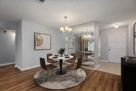 a dining room with wooden floor a glass table and chairs
