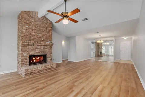 an empty room with wooden floor fireplace and windows