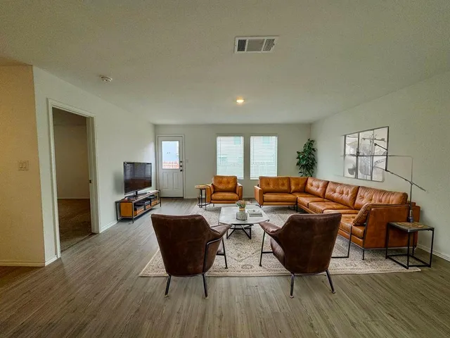 a living room with furniture a wooden floor and a potted plant