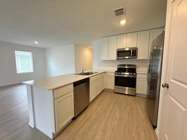 a kitchen with kitchen island a counter top space a sink stainless steel appliances and cabinets