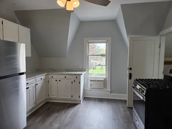a kitchen with granite countertop a refrigerator a sink and wooden floors