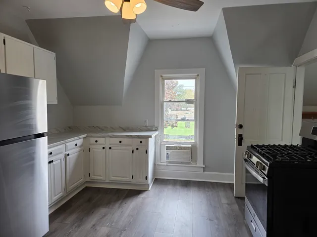 a kitchen with granite countertop a refrigerator a sink and wooden floors