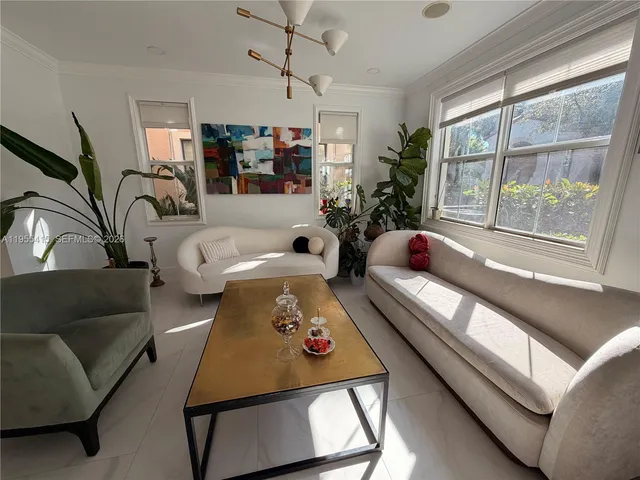 a dining room with furniture a potted plant and a kitchen view