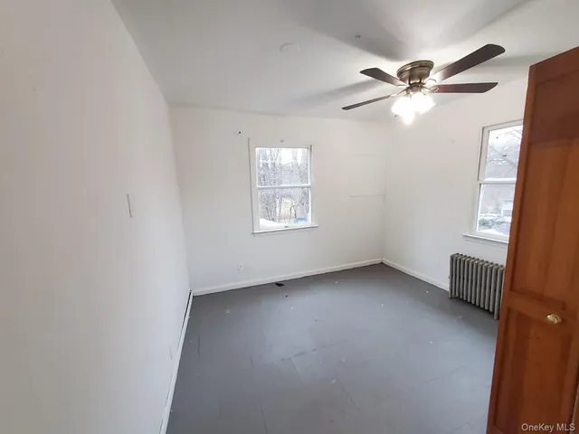 an empty room with windows and fan