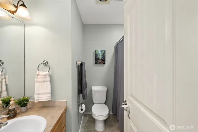 a white toilet sitting next to a bathroom sink and a mirror