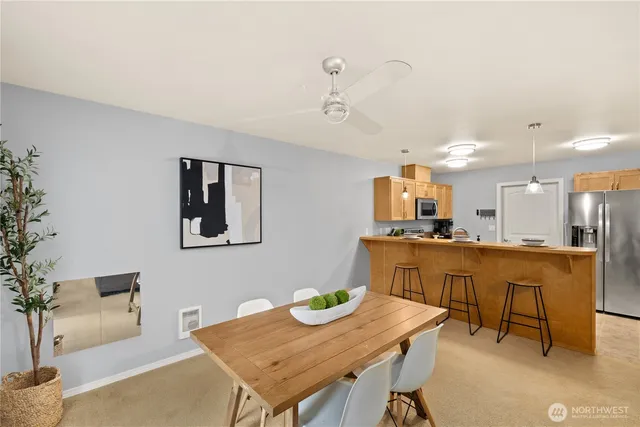 a kitchen with stainless steel appliances kitchen island granite countertop a dining table chairs and a refrigerator
