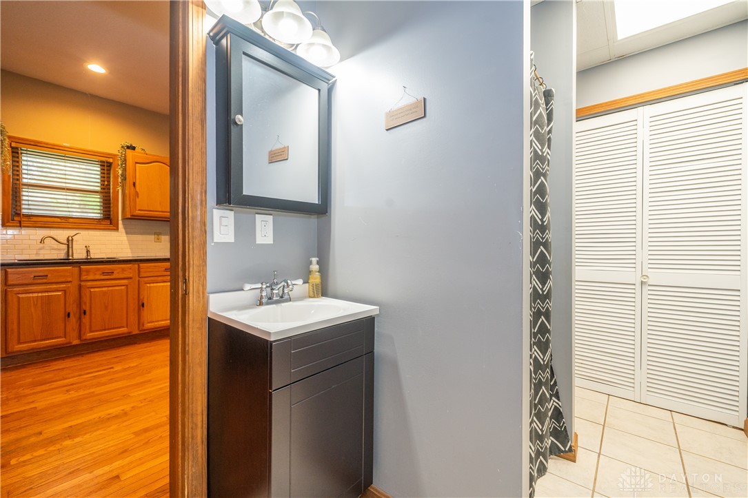 10584 New Biddinger Road Harrison, OH 45030 - Photo 26 of 61 This bathroom features a sleek vanity, mirror, and access to a bright kitchen with wood???????????????????????? flooring.