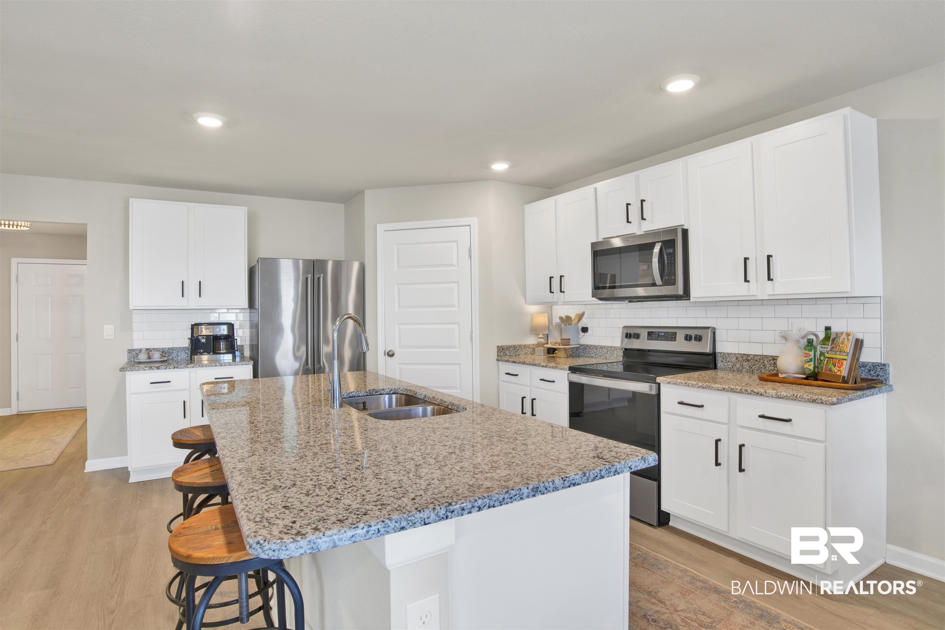 24532 Broken Sound Loop Orange Beach, AL 36561 - Photo 11 of 29 Kitchen with appliances with stainless steel finishes, light hardwood / wood-style flooring, tasteful backsplash, sink, and white cabinets
