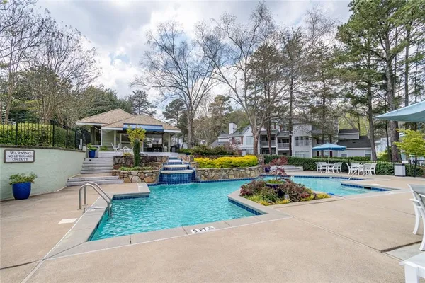 a view of a swimming pool with lawn chairs under an umbrella