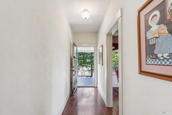 a view of a hallway with wooden floor and a dining room