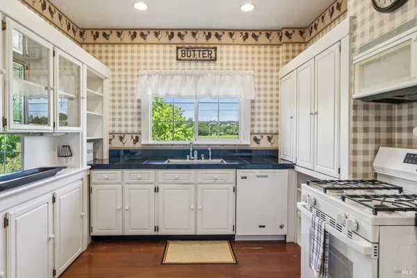 a kitchen with granite countertop white cabinets and white appliances