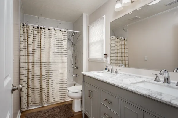 a bathroom with a granite countertop sink toilet and shower