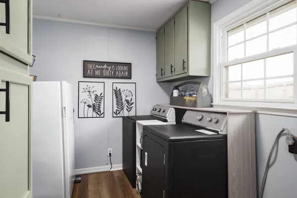 a utility room with fridge and wooden floor