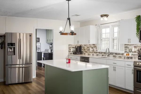 a kitchen with kitchen island a sink appliances a counter space and a window