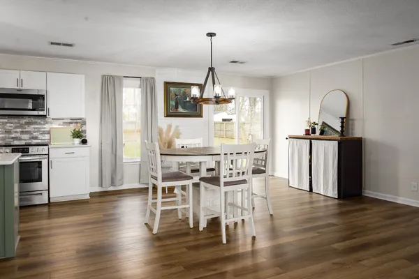 a kitchen with stainless steel appliances granite countertop a dining table chairs stove and wooden floor