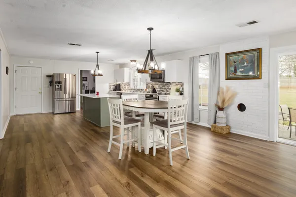 a dining room with furniture a chandelier and wooden floor