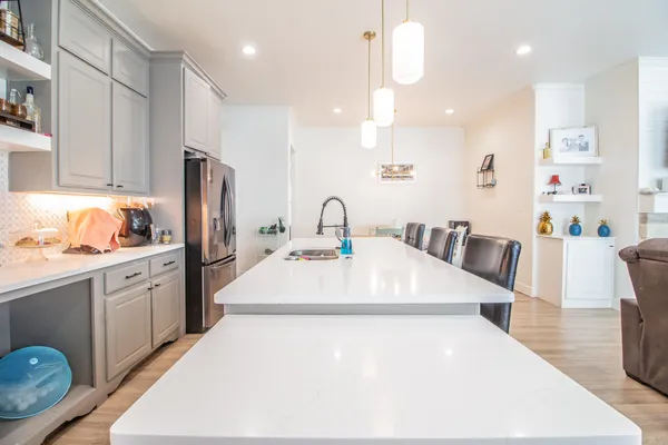 a large white kitchen with a sink a refrigerator and chairs