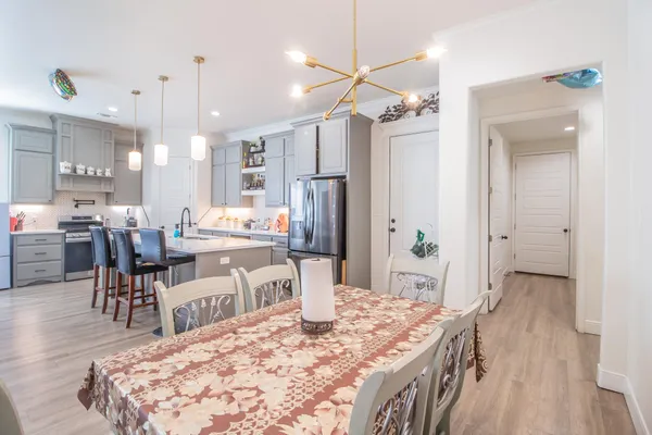 a living room with stainless steel appliances kitchen island granite countertop furniture wooden floor and a chandelier