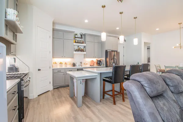 a open kitchen with stainless steel appliances granite countertop a sink dishwasher a stove and a dining table with wooden floor