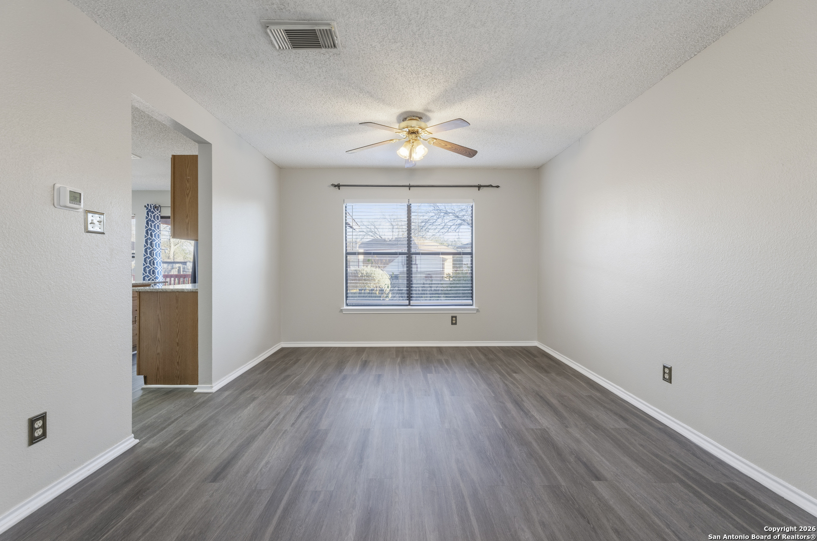 1048 Sycamore Schertz, TX 78154 - Photo 8 of 31 an empty room with wooden floor chandelier fan and windows