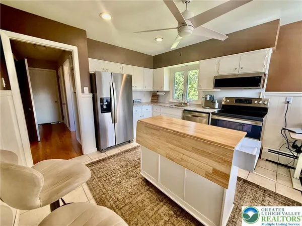 a living room with stainless steel appliances furniture and a flat screen tv