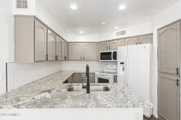 a kitchen with granite countertop white cabinets stainless steel appliances and a counter space