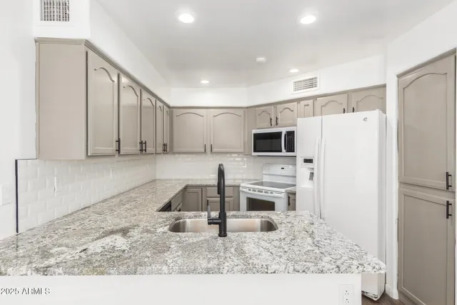 a kitchen with granite countertop white cabinets stainless steel appliances and a counter space