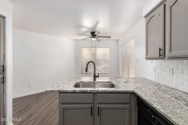 an empty room with wooden floor and ceiling fan