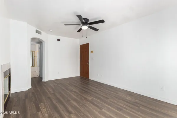 an empty room with wooden floor a ceiling fan and windows