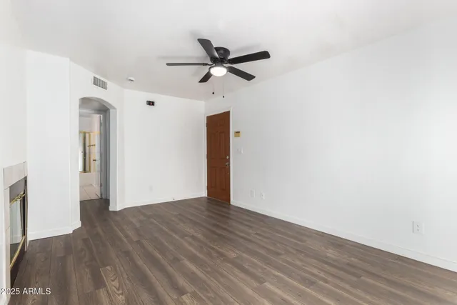 an empty room with wooden floor a ceiling fan and windows