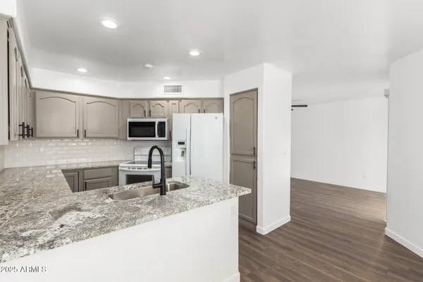 a kitchen with stainless steel appliances kitchen island granite countertop a refrigerator a stove and a sink