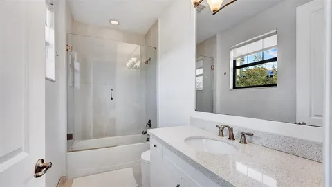 a bathroom with a granite countertop sink a large mirror and a bathtub