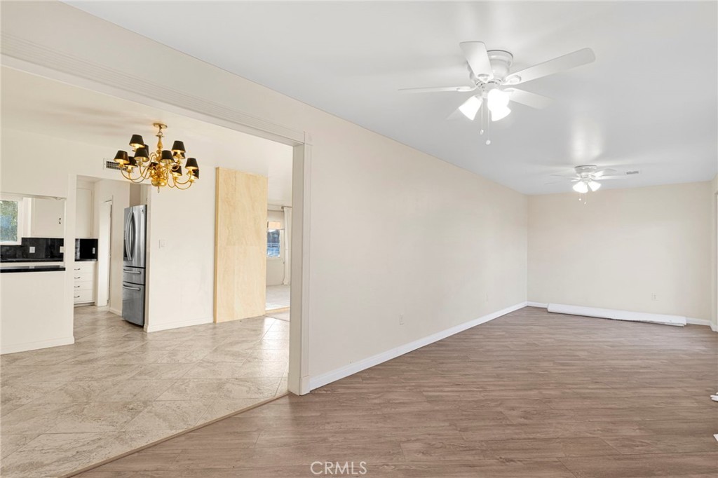 15177 Mendota Road North Apple Valley, CA 92307 - Photo 28 of 50 an empty room with chandelier fan and kitchen view