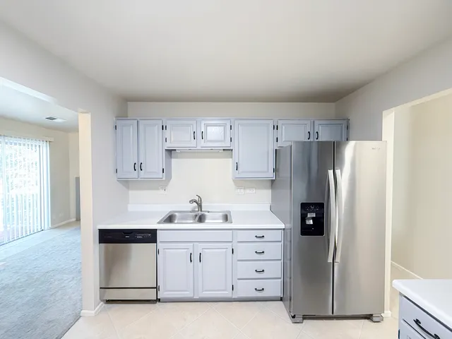 a kitchen with white cabinets and refrigerator