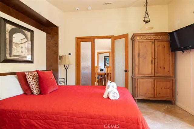 a bedroom with a bed a dresser and flat screen tv