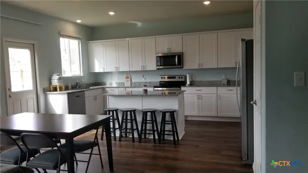a kitchen with stainless steel appliances granite countertop a table chairs microwave and sink