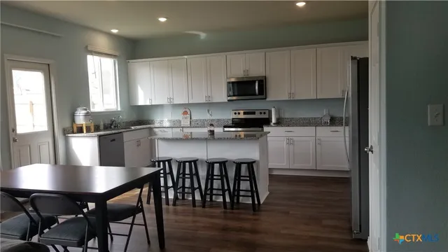 a kitchen with stainless steel appliances granite countertop a table chairs microwave and sink