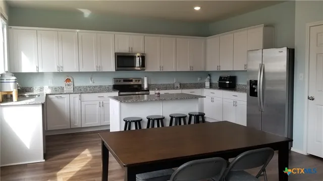 a kitchen with a table chairs refrigerator and cabinets