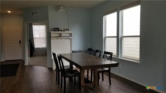 a kitchen with stainless steel appliances granite countertop a kitchen island hardwood floor a dining table and chairs