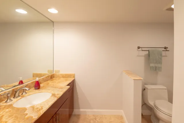 a bathroom with a granite countertop sink a toilet and a mirror