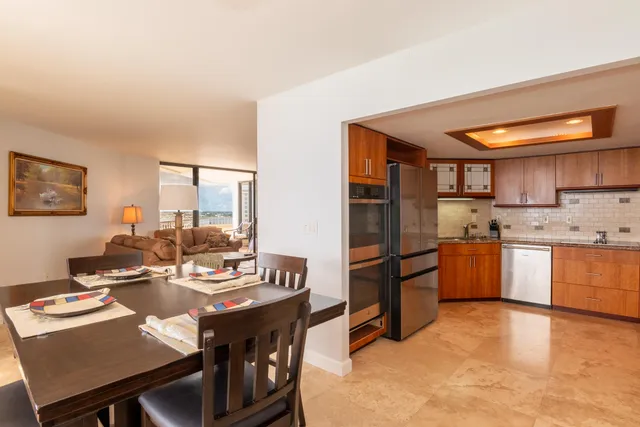 a kitchen with stainless steel appliances kitchen island granite countertop a table chairs and a refrigerator