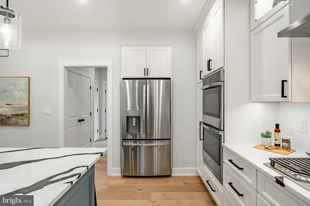 a kitchen with stainless steel appliances granite countertop a sink a stove a dining table and chairs with wooden floor